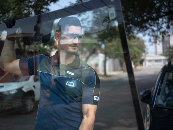 Profissional carregando um parabrisa para instalação em um serviço da autoglass